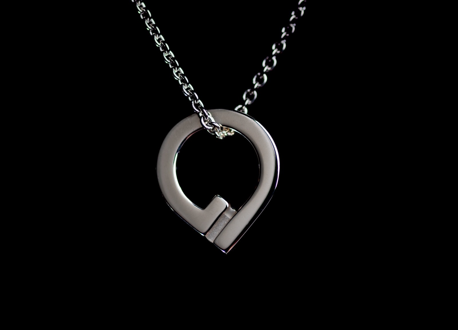 The Mementum object worn on a chain: a polished sterling silver setting on black